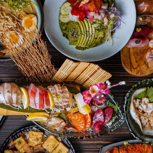 A vibrant spread of Sushiya's sushi, sashimi, ramen, and other Japanese dishes on a dark wooden table.