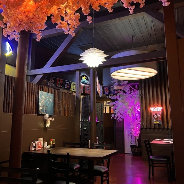 Sushiya's dining area with wooden tables, bamboo walls, and cherry blossom decor under soft lighting.