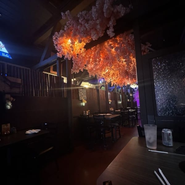 Sushiya's dimly lit dining room with cherry blossom decor, bamboo partitions, and empty tables.