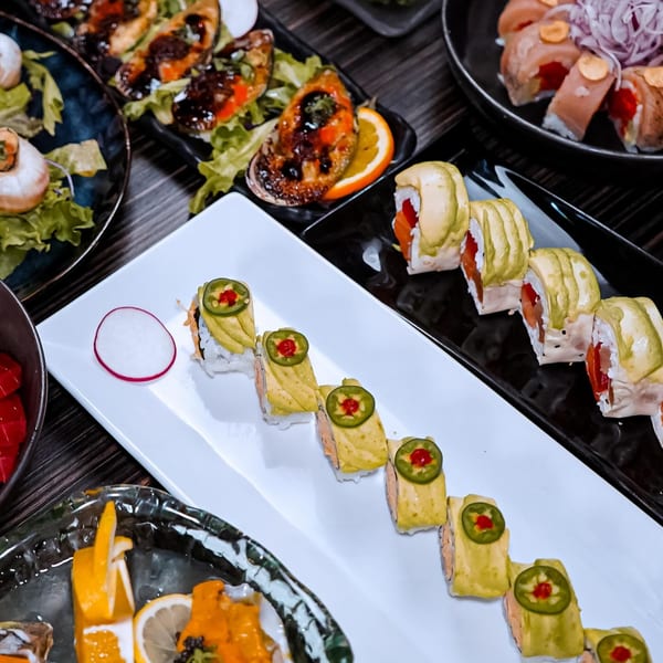 Sushiya's sushi rolls with avocado and jalapeño, alongside other seafood dishes on a dark table.