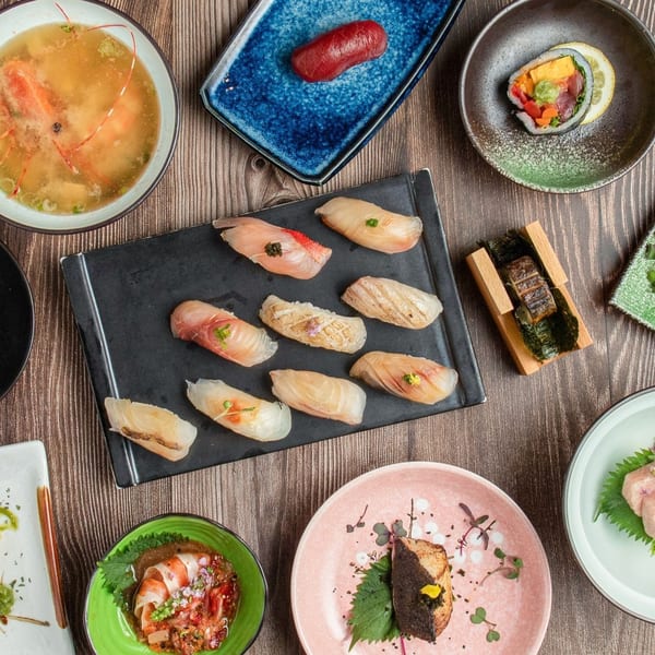 An overhead shot of various Japanese dishes, including sushi, soup, and other small plates.