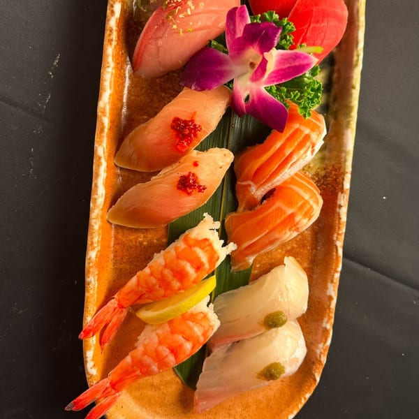 A vibrant platter of Sushiya's assorted sushi and sashimi, garnished with an orchid and lemon.