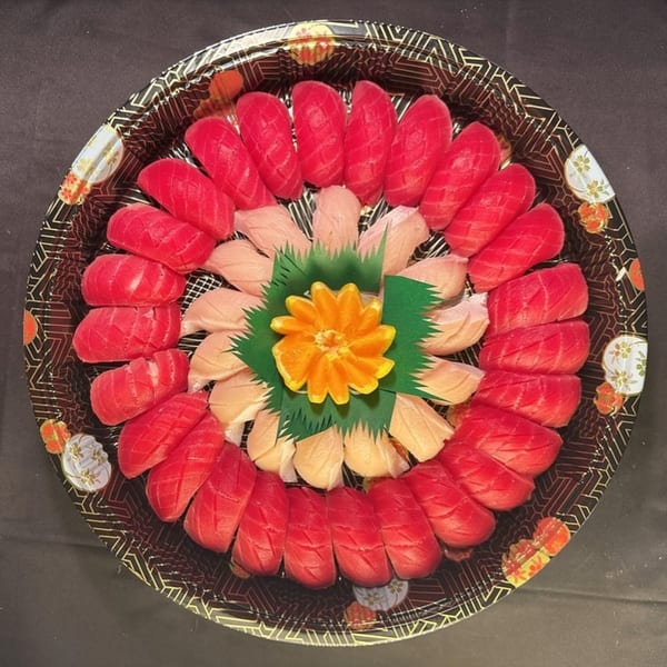 Sushiya's sushi platter with red tuna and light-colored fish, garnished with an orange flower.