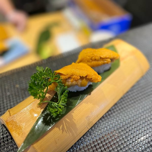 Two pieces of uni sushi with parsley on a bamboo serving dish at Sushiya.