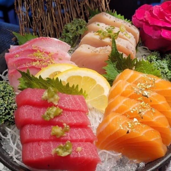 A colorful sashimi platter with tuna, salmon, and white fish, garnished with lemon and greens.