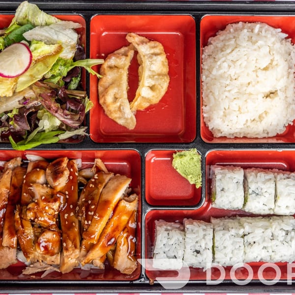 Bento box with teriyaki chicken, sushi rolls, rice, salad, gyoza, and wasabi.
