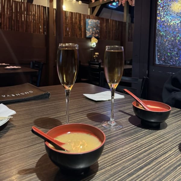 Two champagne flutes and two bowls of miso soup on a table at Sushiya restaurant.